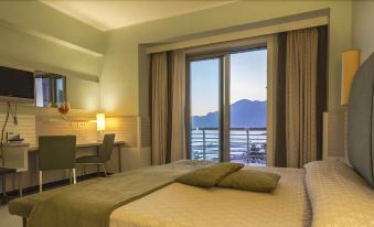 a hotel room with a large window overlooking the ocean , featuring a bed , a desk , and a chair at Grand Hotel Salerno