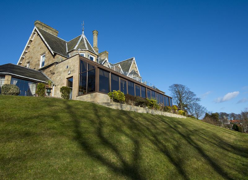 a large , stone building situated on top of a hill with a grassy lawn in front of it at Old Manor Hotel