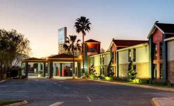 a large hotel building with palm trees and a sign in front of it at dusk at Four Points by Sheraton Saltillo