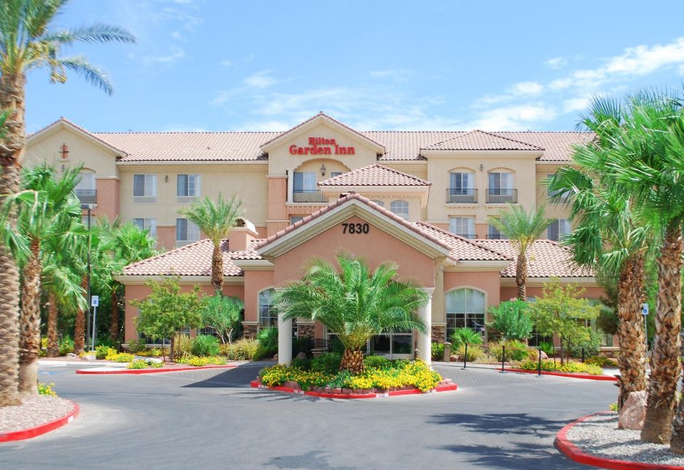 a hotel with a large building , surrounded by palm trees and other greenery , under a clear blue sky at Hilton Garden Inn Las Vegas Strip South