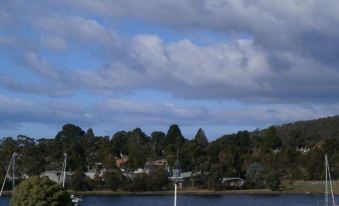 a picturesque view of a small town by the water , with boats floating in the water and trees lining the shore at Waterfront Lodge Motel