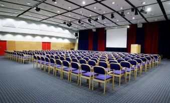 a large conference room with rows of blue chairs and a projector screen at the front at Thon Hotel Oslofjord