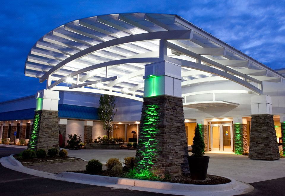 an entrance to a hotel at night , with a large stone pillar in the foreground at Holiday Inn Grand Haven-Spring Lake