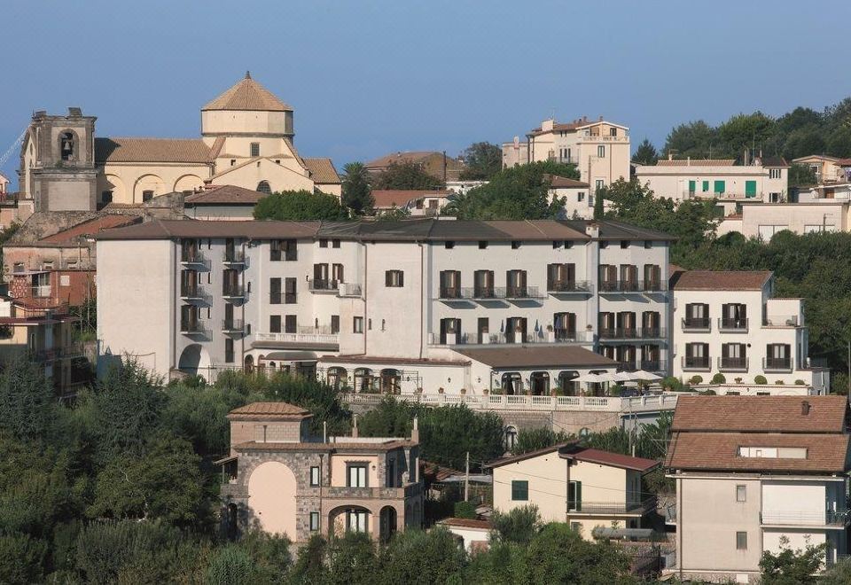 a large building with a dome is situated on a hillside , overlooking other buildings and trees at Hotel Jaccarino