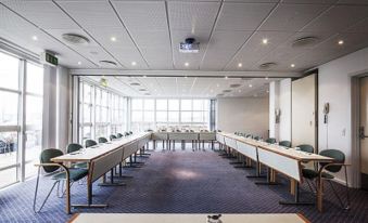 a large conference room with long tables and chairs arranged in rows , providing seating for a group of people at Pier 5 Hotel