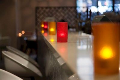 a red candle on a table , next to a glass of beer , with a blurred background at Ibis Melbourne Hotel and Apartments