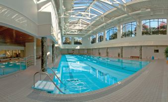 an indoor swimming pool surrounded by a glass wall , allowing natural light to fill the space at Hotel Grand Pacific