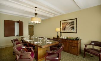 a dining room with a wooden table surrounded by chairs , a large painting on the wall , and a chandelier hanging above at Best Western Plus Madison-Huntsville Hotel