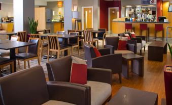 a modern cafe with several chairs and couches , as well as tables and a counter at Holiday Inn Express Droitwich Spa