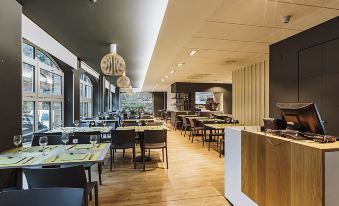 a modern restaurant with wooden floors and tables , black chairs , and white pendant lights at Hotel Urdanibia Park