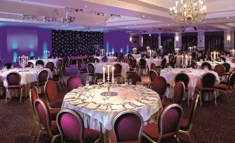 a large banquet hall filled with round tables and chairs , where several people are seated at Macdonald Inchyra Hotel and Spa