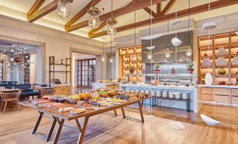 a large dining room with a buffet table filled with various food items , including fruits , vegetables , and meats at Cap Vermell Grand Hotel