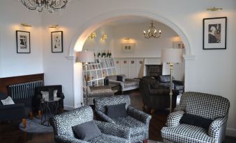a well - decorated living room with various seating options , including couches and chairs , under a large archway at Low Wood Bay