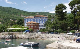 a blue building with a red roof is situated on a hillside near the water at Hotel Park