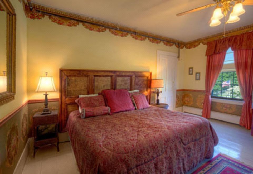a large bed with a wooden headboard and red bedding is in a room with two lamps at Gibson House