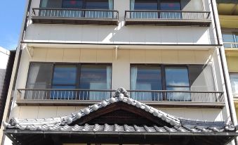 a building with a traditional japanese roof and balconies , surrounded by trees and a clear blue sky at Sakuraya
