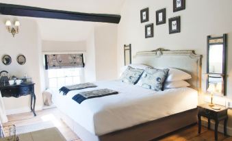 a white bedroom with a large bed and multiple pictures on the wall , creating a cozy atmosphere at The White Hart