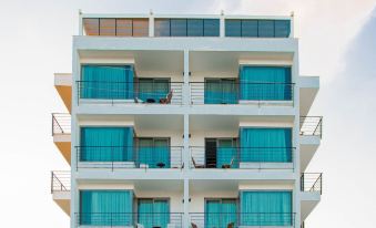 a white building with blue balconies and windows is shown against a cloudy sky at Port Marina Hotel