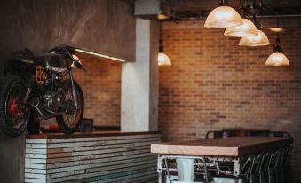 a dining room with a motorcycle hanging on the wall , a table with chairs , and a brick wall at The Bricks Hotel