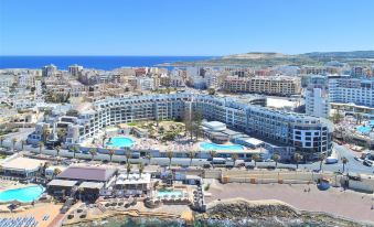 a large resort with multiple buildings and a swimming pool is situated near the ocean at DoubleTree by Hilton Malta