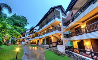 a multi - story building with balconies and a tree in front of it , lit up at night at Mida Resort Kanchanaburi