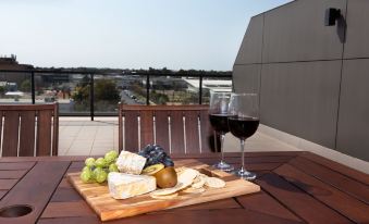 a wooden cutting board with cheese and grapes is placed on a table next to two wine glasses at The Penthouse
