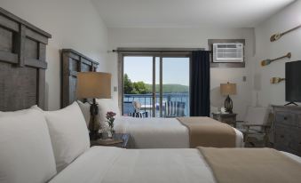 a hotel room with two twin beds , a balcony overlooking a body of water , and air conditioning units on the wall at Lake Bomoseen Lodge