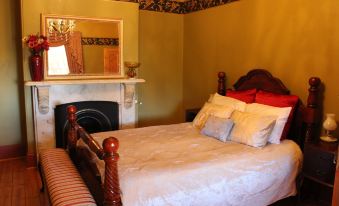 a cozy bedroom with a large bed , a fireplace , and a mirror above the bed at Copper House