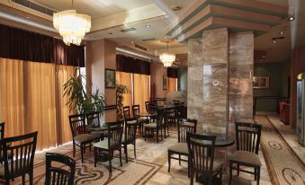 a well - lit dining room with tables and chairs arranged for a group of people to enjoy a meal at Hotel Regency