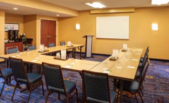 a large conference room with multiple rows of chairs arranged in a semicircle around a table at Courtyard Detroit Dearborn