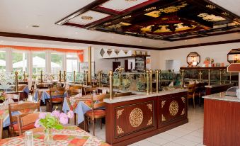 a restaurant with a large dining table surrounded by chairs , and a buffet filled with various food items at Lotus