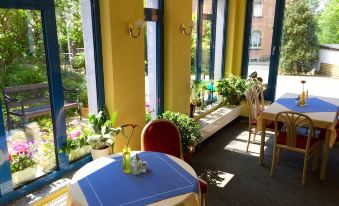 a brightly lit dining room with several tables and chairs arranged for a group of people at Schöne Aussicht