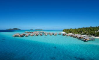 a luxurious resort with multiple bungalows , surrounded by crystal blue water and lush green trees at Le Bora Bora by Pearl Resorts