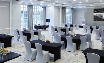a large , well - lit conference room with multiple tables and chairs set up for an event or meeting at Forest of Arden Country Club