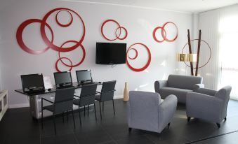 a modern office space with multiple chairs arranged around a table , and several computers on the desks at Idea Hotel Milano Malpensa Airport