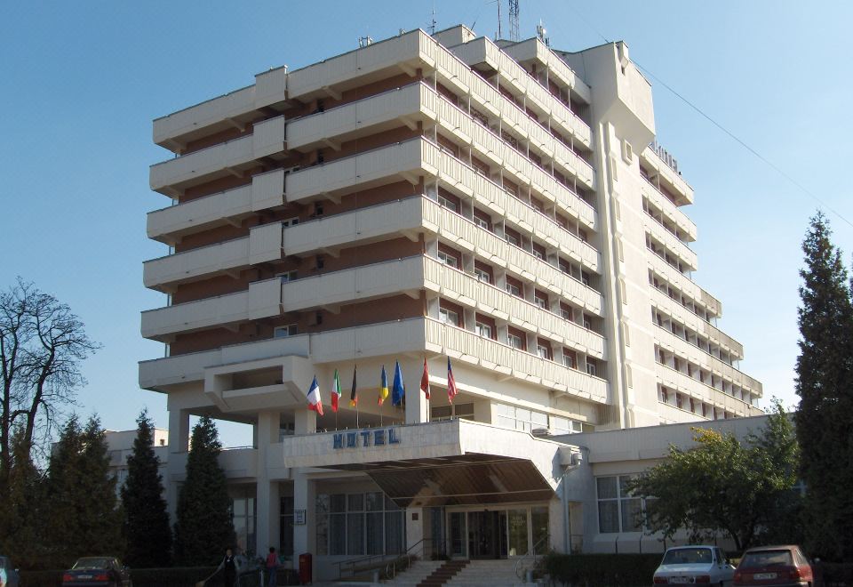 "a large white hotel building with multiple flags and a sign that says "" hotel ""." at Hotel Belvedere