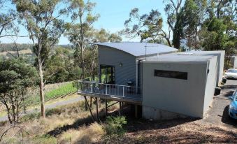 A rural house on the top floor level with an attached deck and balcony that overlook the water at Armalong Winery Chalets