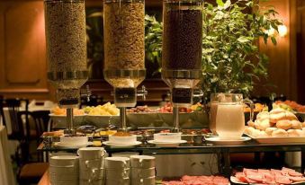 a buffet table with various food items and drinks , including a glass of milk and a bowl of cereal at Park Plaza Apartments