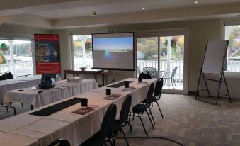 a conference room with a projector screen , tables , and chairs set up for an event at Sportsman's Inn Resort & Marina