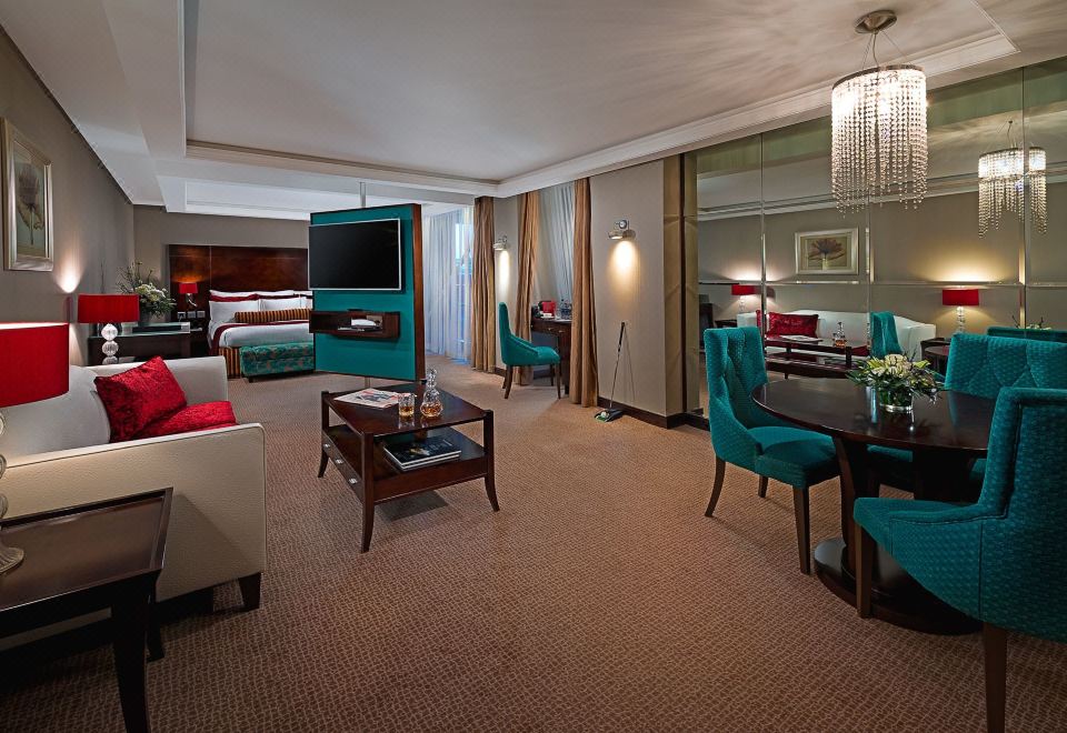 a luxurious hotel room with a comfortable bed , a flat - screen tv , a dining table , and a living area at The Savoy Hotel