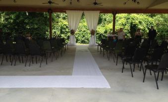 a wedding ceremony taking place under a covered pavilion , with chairs arranged for guests at Bicentennial Inn