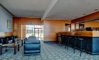 a modern bar area with blue leather chairs and a wooden counter , surrounded by wooden walls at VIP Executive Santa Iria Hotel