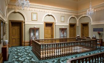 a grand room with ornate decorations , including chandeliers and doors , under a green carpeted floor at Tre-Ysgawen Hall & Spa