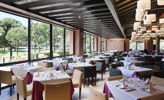 a large , well - lit dining room with multiple tables and chairs arranged for a group of people to enjoy a meal together at DoubleTree by Hilton Islantilla Beach Golf Resort