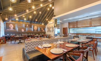 a modern restaurant with wooden tables , chairs , and tables set for diners , along with a bar area at Emotions by Hodelpa - Juan Dolio