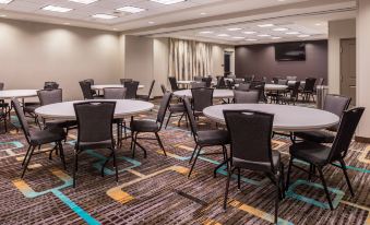 a conference room with several round tables and chairs , a carpeted floor , and a television at Residence Inn St. Louis Westport