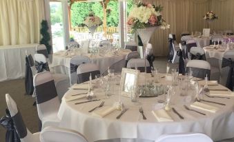 a well - decorated dining room with multiple round tables covered in white tablecloths and surrounded by chairs at Rettendon Lodge