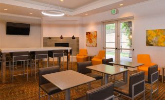 a modern hotel lobby with various seating options , including chairs and couches , as well as a television mounted on the wall at Residence Inn Palo Alto Los Altos