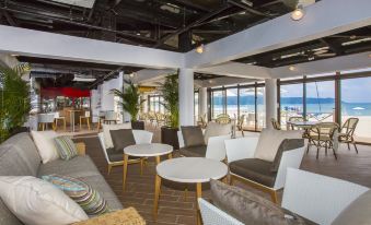 a modern , open - air seating area with white furniture and large windows offering views of the ocean at Okuma Private Beach & Resort