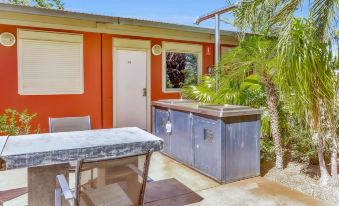 a small , orange house with a patio area featuring a table and chairs , a refrigerator , and a grill at Econo Lodge Karratha